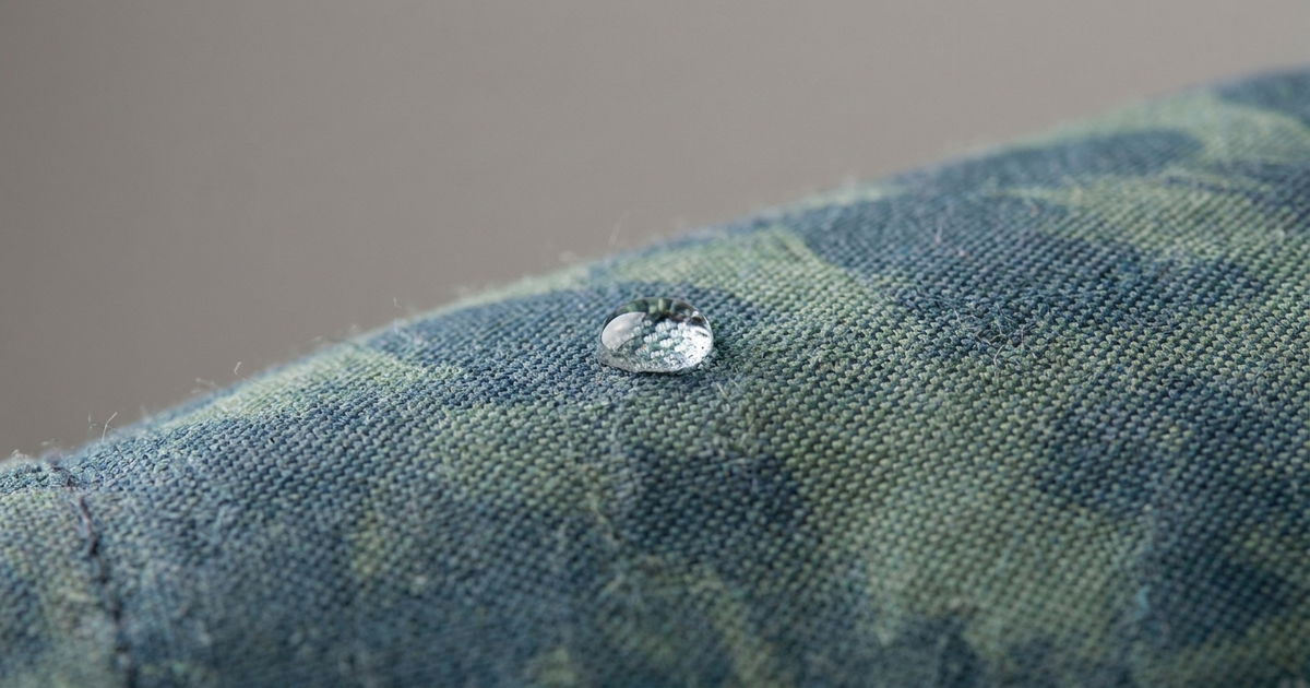 A child's school backpack with a water droplet beading off the fabric surface, close-up texture shot, neutral studio background A child's school backpack with a water droplet beading off the fabric surface, close-up texture shot, neutral studio background